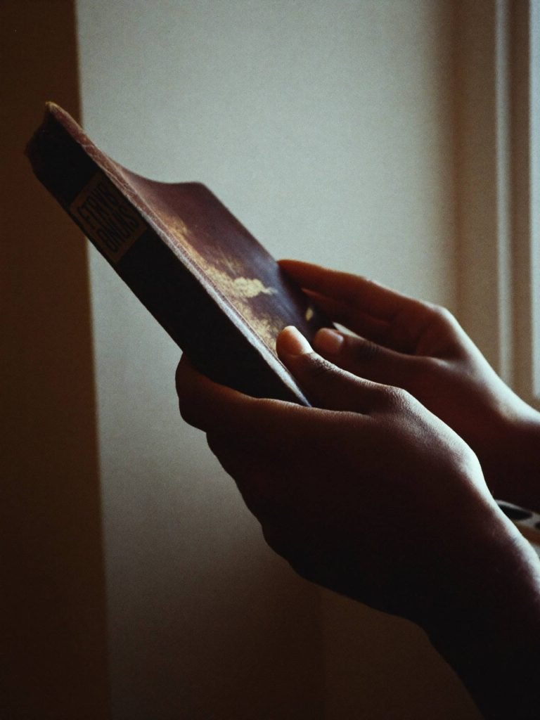 Placeholder — intended image: Close-up of hands slowly opening Scripture in low natural light